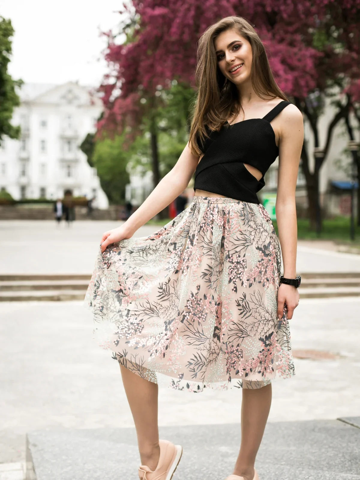 Model wearing a floral skirt showcasing women's fashion skirts in a park setting.