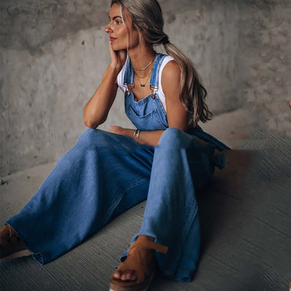 Woman in women's wide-leg denim overalls sitting stylishly on the floor, showcasing trendy street fashion.