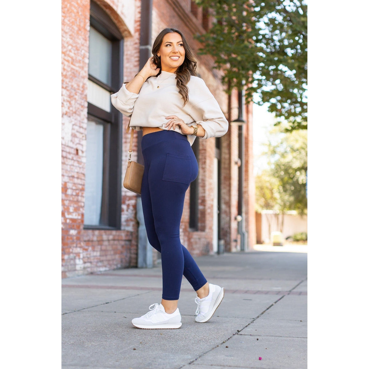 Woman wearing navy full-length leggings with pockets, styled with a cropped sweater and white sneakers.