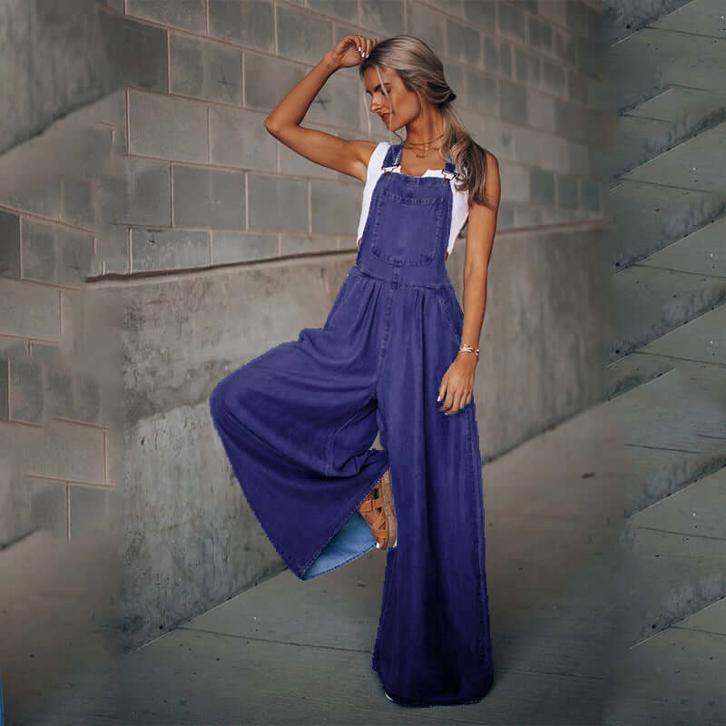 woman wearing women's wide-leg denim overalls in a stylish pose against a textured wall