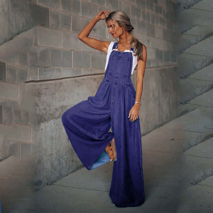 woman wearing women's wide-leg denim overalls in a stylish pose against a textured wall
