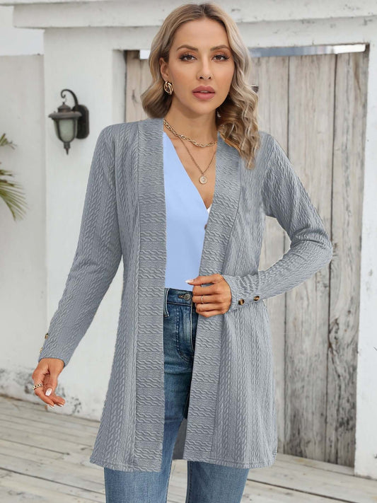 A woman wearing a women's knit cardigan in gray, featuring a button-down front and relaxed silhouette.