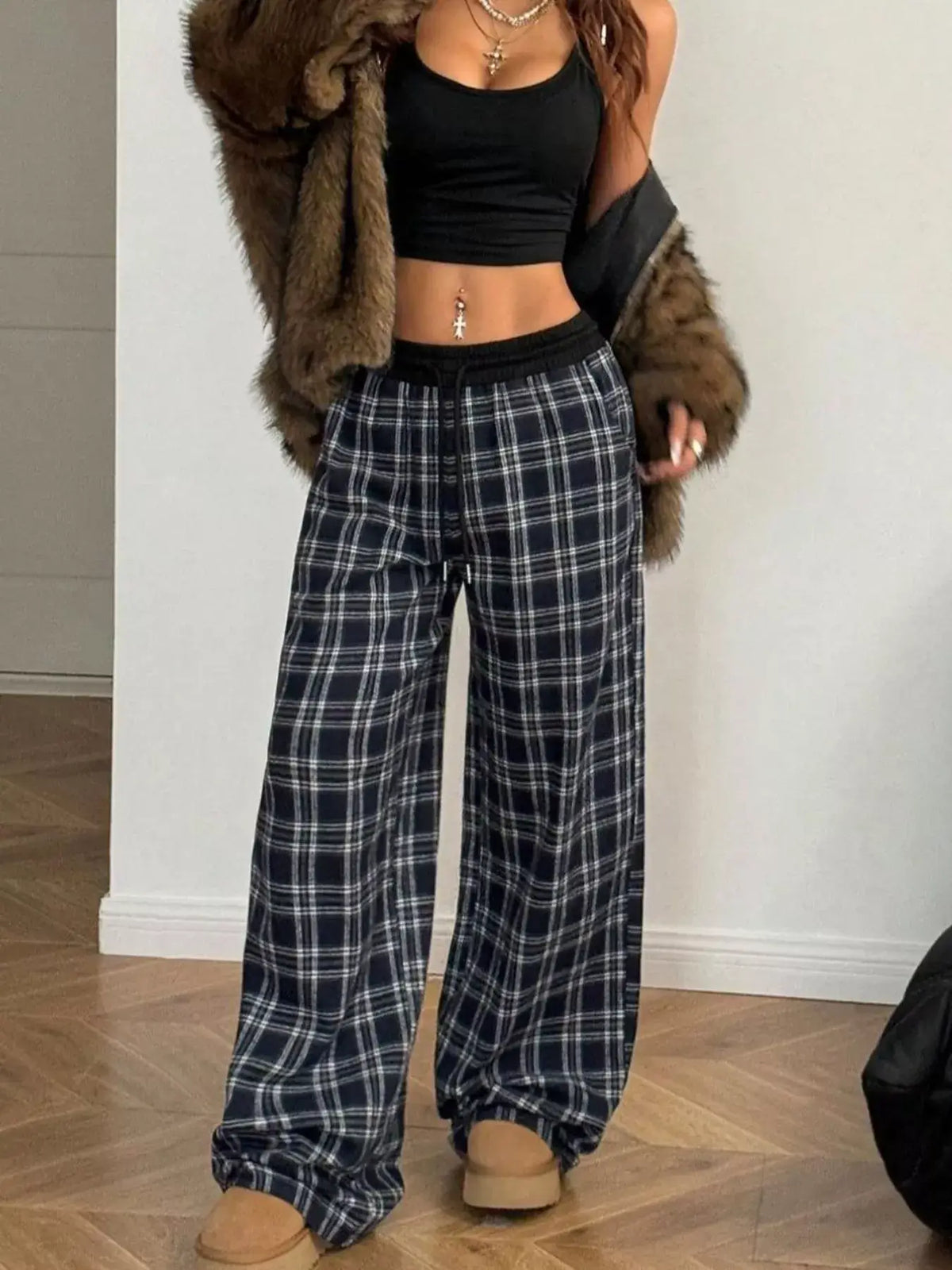 Women's relaxed plaid pants in a stylish outfit, paired with a black crop top and a fur coat.