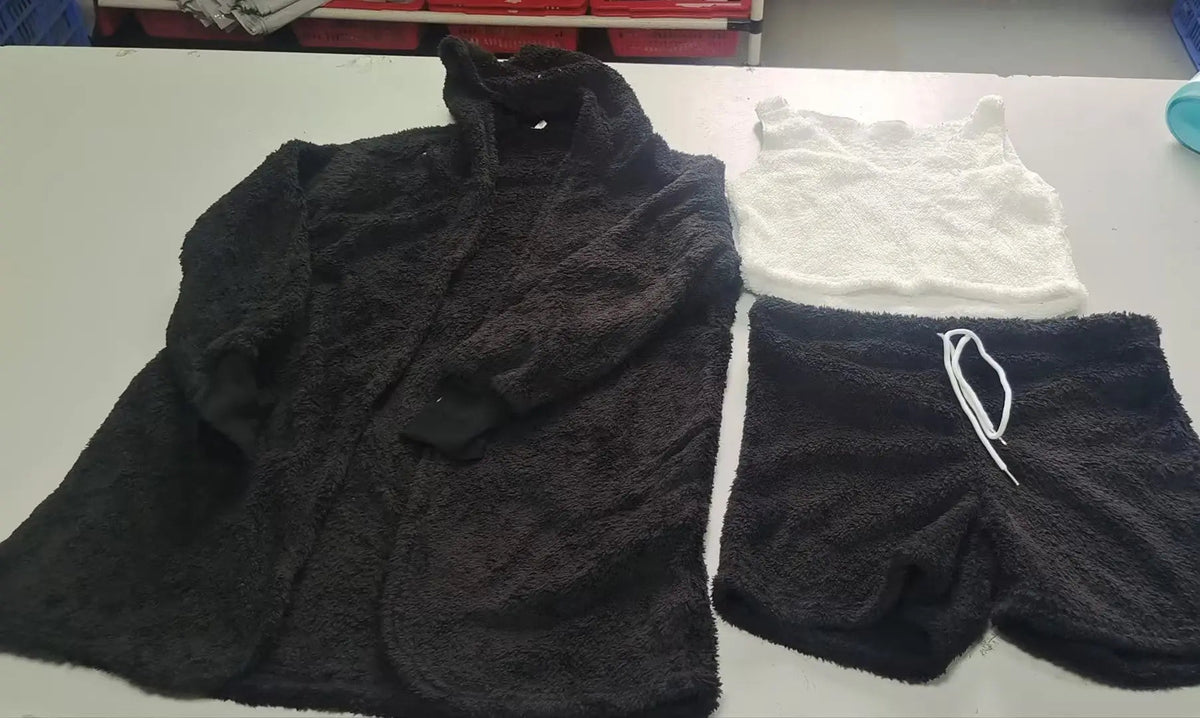 Flat lay of the black hooded cardigan, white cami top, and black drawstring shorts