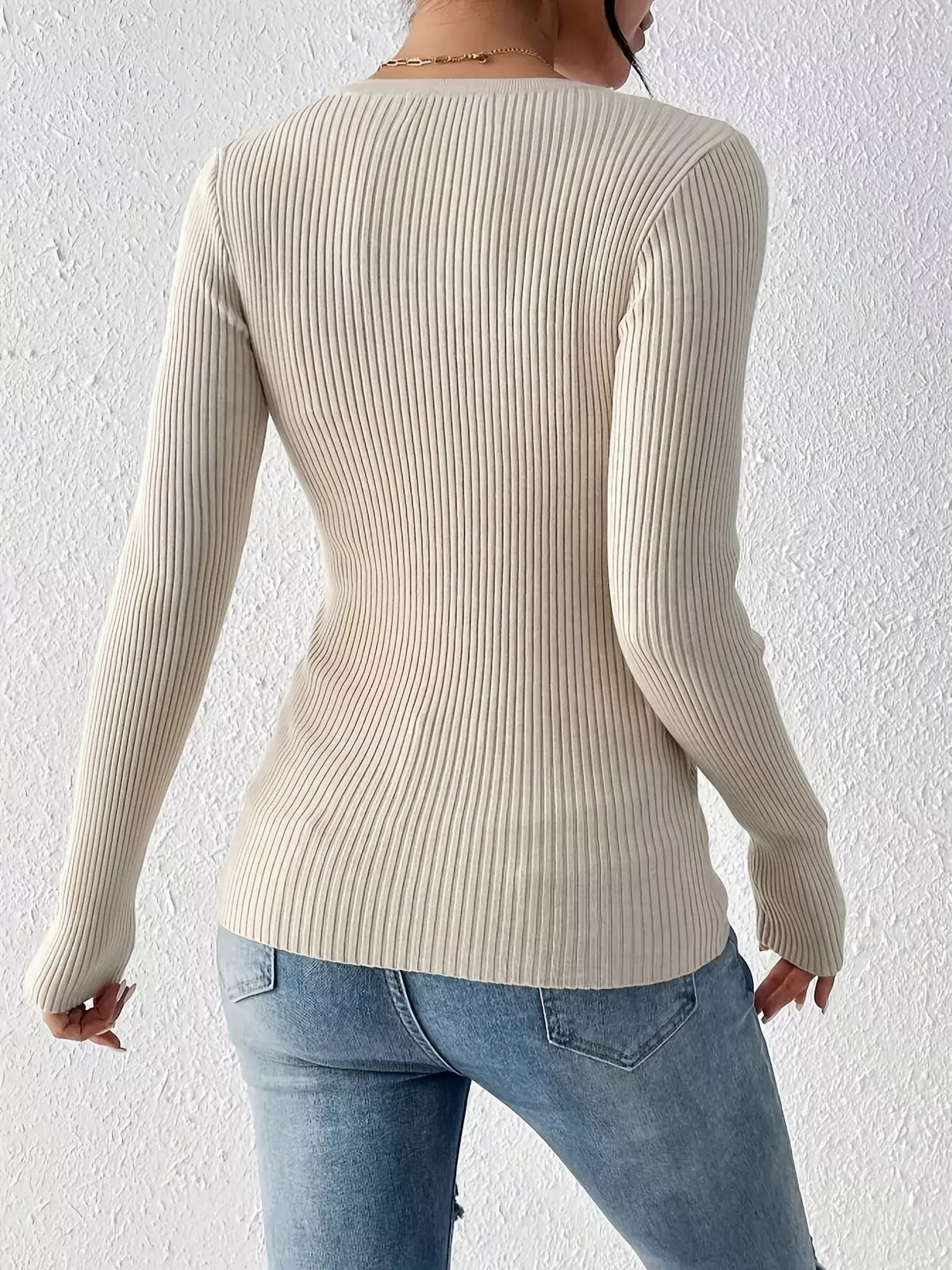 Back view of a model wearing a ribbed knit button front top with long sleeves and casual jeans.