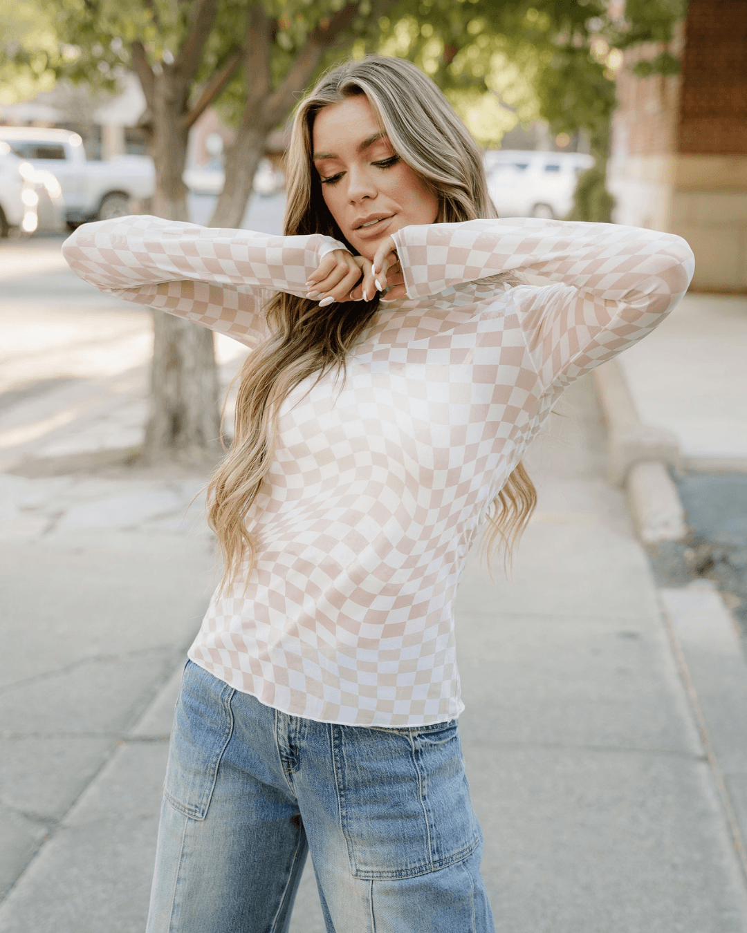 Model wearing a khaki sheer checkered top, showcasing its stylish design and lightweight fabric.
