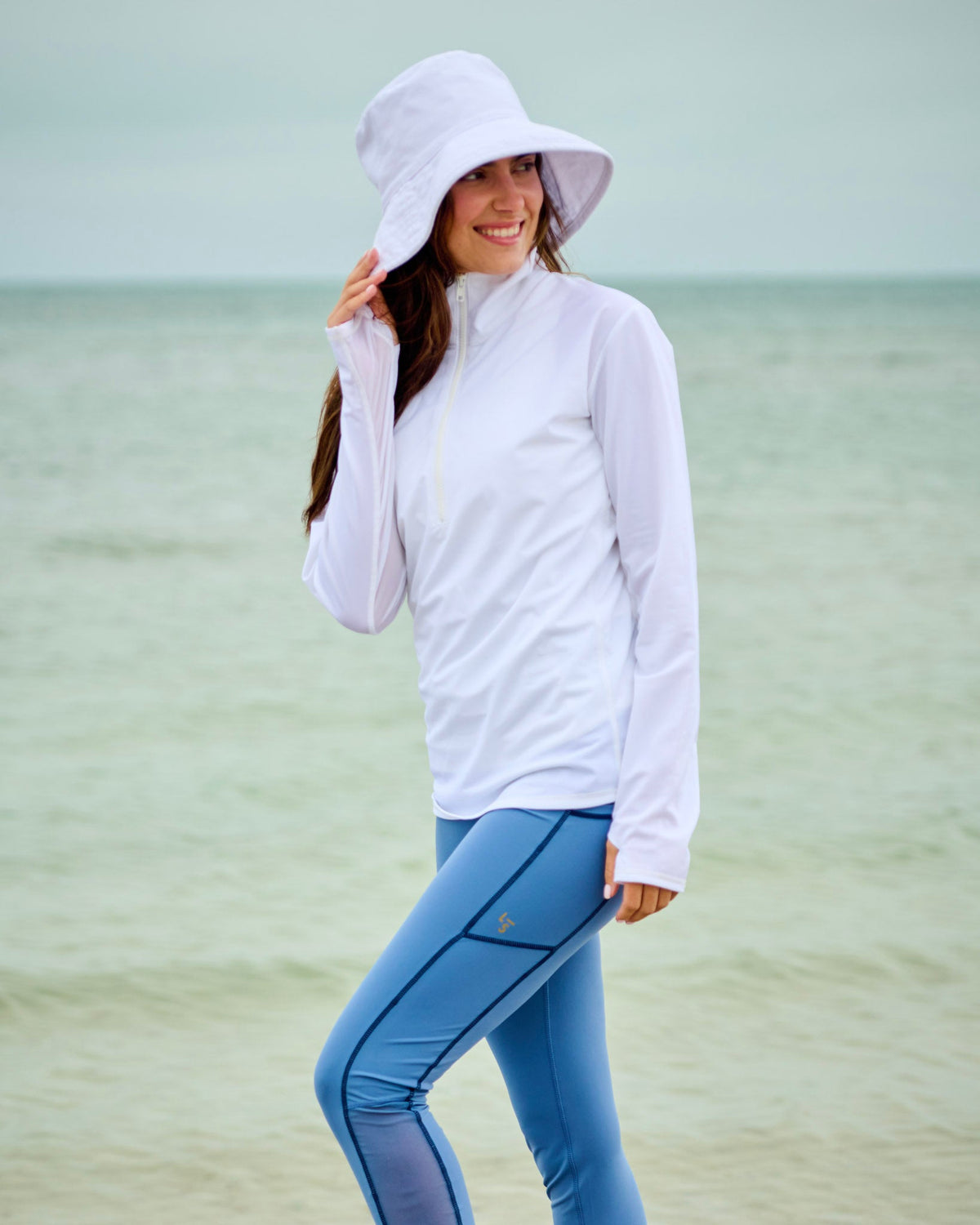 Woman wearing high-performance swim leggings and sun protection shirt at the beach