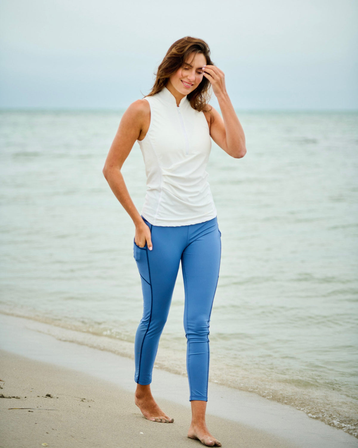 Model wearing high-performance swim leggings on the beach, showcasing comfort and style in outdoor activities.
