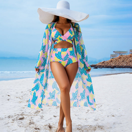 Model wearing a printed padded bikini set with a cover-up hat at the beach, showcasing vibrant tropical patterns.