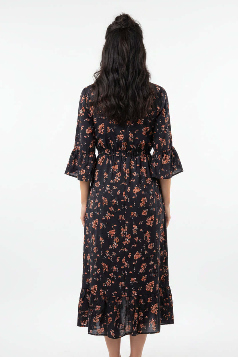Back view of a woman wearing a floral denim patchwork midi dress with bell sleeves and a cinched waist.
