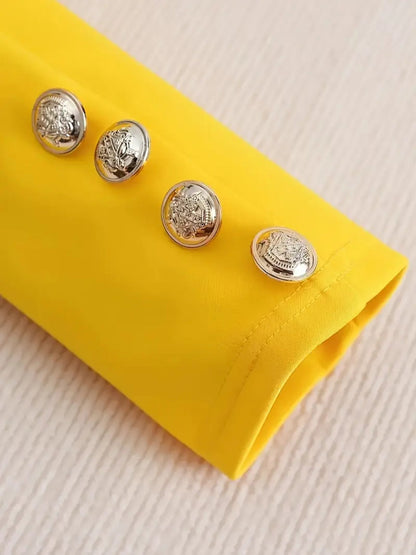 Close-up of silver buttons on a vibrant yellow sleeve of a womens printed pants suit.