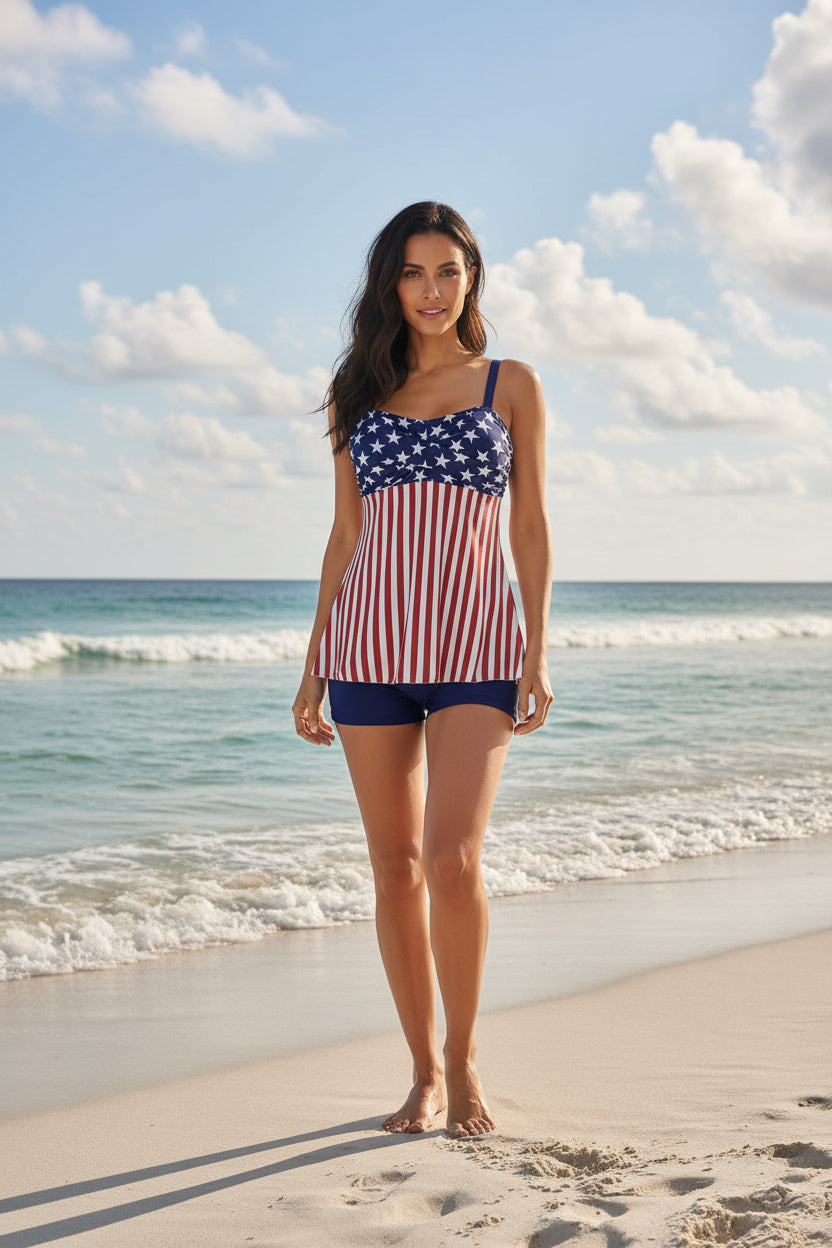 Woman in a printed two-piece swimsuit set with patriotic design standing on the beach by the ocean.